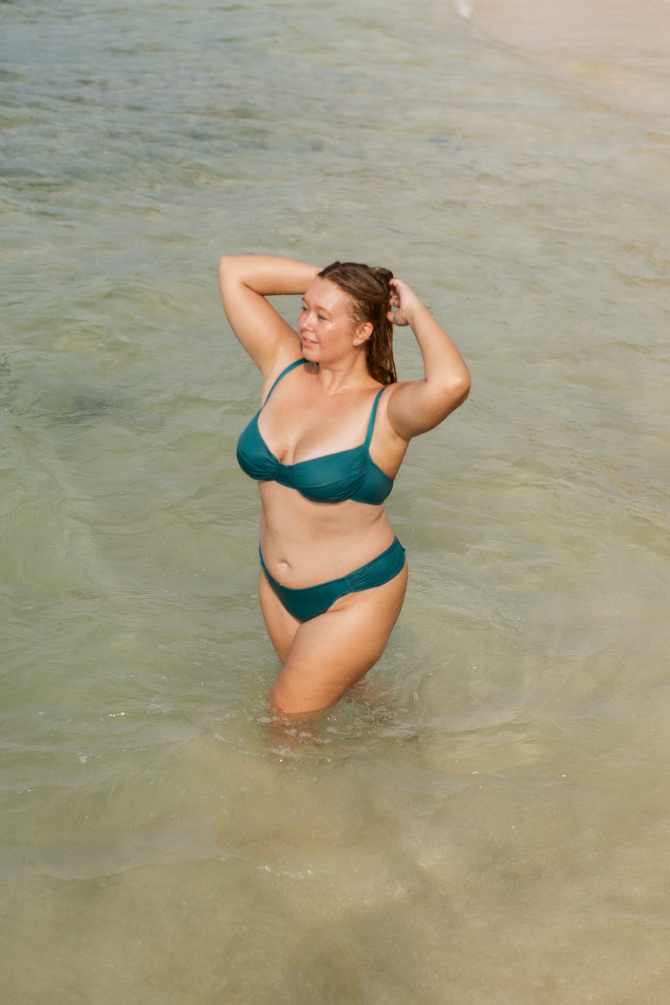Teal gathered top with ruched front and thin straps, worn in shallow water, lifestyle view
